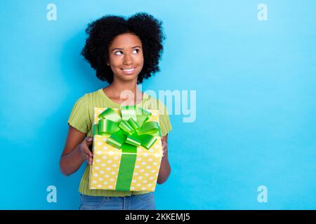 Photo de petit mignon gai rêveur adolescent école tenir cadeau nouvel anniversaire surprise de parents look vide espace isolé sur la couleur bleue Banque D'Images