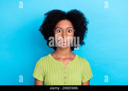 Photo de positive excitée surprise fille avec perming coiffure porter t-shirt vert sans voix isolé sur fond bleu Banque D'Images