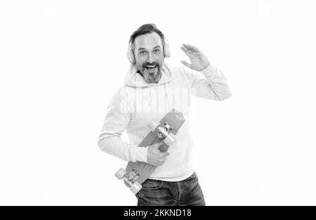 joyeux skateboarder écoutez de la musique dans les écouteurs tenez le skateboard isolé sur blanc, en s'amusant. Banque D'Images