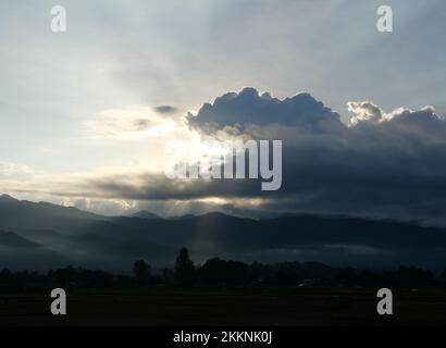 Silhouette d'arbre et de montagne avec la lumière de sunbeam pousse à travers le nuage sombre jusqu'à la terre au lever du soleil, Mist couvre la forêt et les montagnes à l'aube Banque D'Images