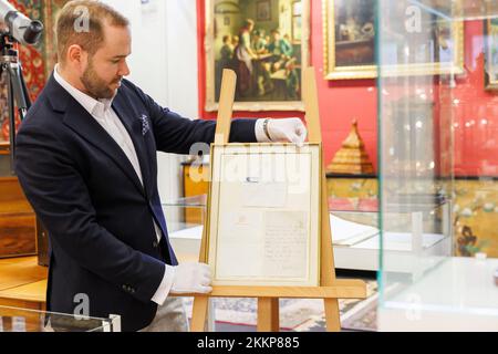 Leinfelden Echterdingen, Allemagne. 25th novembre 2022. La maison de vente aux enchères Eppli à Stuttgart, outre d'autres objets sur le thème de la « royauté britannique », une lettre manuscrite de deux pages de la Reine Elizabeth II (1926-2022) récemment décédée de 1966 à un équestre passionné. Ferdinand Eppli (membre de la direction de l'entreprise familiale Eppli) présente l'objet à mettre aux enchères. C'est la lettre encadrée, une copie du dos et de l'enveloppe. Crédit : Julian Rettig/dpa/Alay Live News Banque D'Images