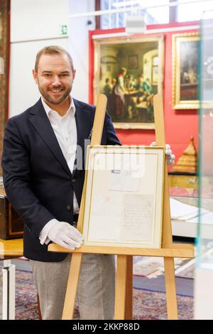 Leinfelden Echterdingen, Allemagne. 25th novembre 2022. La maison de vente aux enchères Eppli à Stuttgart, outre d'autres objets sur le thème de la « royauté britannique », une lettre manuscrite de deux pages de la Reine Elizabeth II (1926-2022) récemment décédée de 1966 à un équestre passionné. Ferdinand Eppli (membre de la direction de l'entreprise familiale Eppli) présente l'objet à mettre aux enchères. C'est la lettre encadrée, une copie du dos et de l'enveloppe. Crédit : Julian Rettig/dpa/Alay Live News Banque D'Images