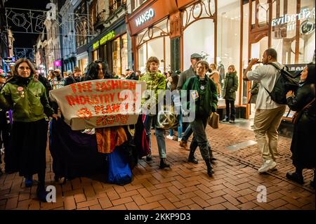 Amsterdam, pays-Bas. 25th novembre 2022. Un activiste XR marche dans les rues en portant une robe fluide faite de différents matériaux en tissu et en tenant une bannière pendant la démonstration de la rébellion du Vendredi fou. L'organisation pour le climat, extinction Rebellion (XR) a organisé une manifestation contre la surconsommation pendant le Vendredi fou, et pour mettre fin à ce jour. Les activistes ont mené une action appelée Free (ky) Friday sur la place du Dam où ils ont placé des centaines de vêtements de seconde main que les gens pouvaient emporter gratuitement ou échanger des vêtements. Avec cette action, l'organisation veut p Banque D'Images