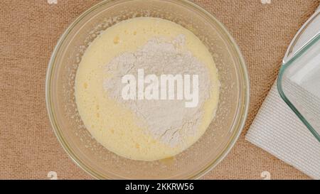 Recette de gâteau aux pommes avec base de biscuit, processus de cuisson étape par étape.Mélanger les œufs, le sucre et la farine dans un bol en verre, poncer à plat.Gros plan des ingrédients sur le kit Banque D'Images