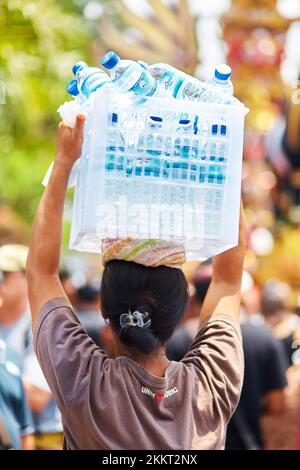 Un vendeur de rue porte ses marchandises sur sa tête. Un moyen de porter des poids sur la tête. Bali, Indonésie - 03.02.2018 Banque D'Images