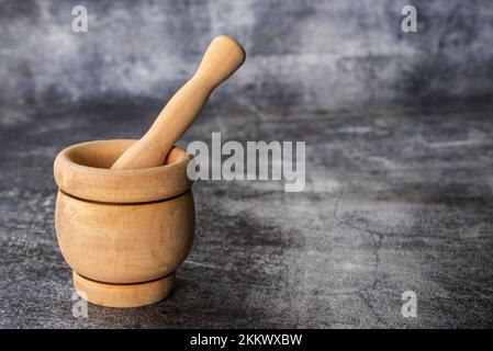 Mortier en bois, ustensile de cuisine pour la purée, sur fond de pierre grise. Banque D'Images