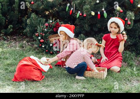 Joyeux Noël.Portrait de trois enfants drôles filles dans le chapeau de Santa manger des biscuits de pain d'épice boire du chocolat chaud à l'extérieur d'avoir du plaisir.Bon Holyn Banque D'Images