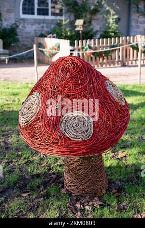Tabouret rouge et blanc, une sculpture tissée sur la faune et la flore du saule dans un grand jardin Banque D'Images