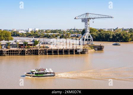 Les bateaux-bus Navibus du réseau de transports publics de Nantes (TAN) naviguent sur la Loire, passant par la grue grise Titan sur l'île de Nantes, en France. Banque D'Images