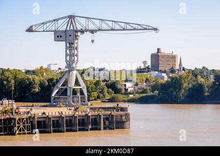 Vue sur la grue grise Titan sur l'île de Nantes, en France, au bord de la Loire avec le bâtiment Maison Radieuse par le Corbusier au loin. Banque D'Images