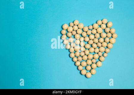 Boules de chocolat blanc en forme de coeur sur fond bleu Banque D'Images