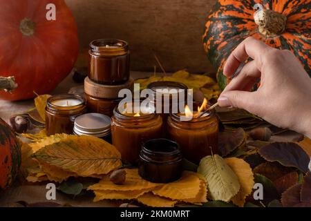 les bougies de soja légères brûlent dans des pots en verre. Feuilles d'arbre, citrouille. Confort à la maison. Bougie dans un pot brun. Parfum et lumière. Bougie parfumée faite à la main. Aromathérapie. Ambiance d'automne. Décoration chaleureuse à l'automne. Banque D'Images
