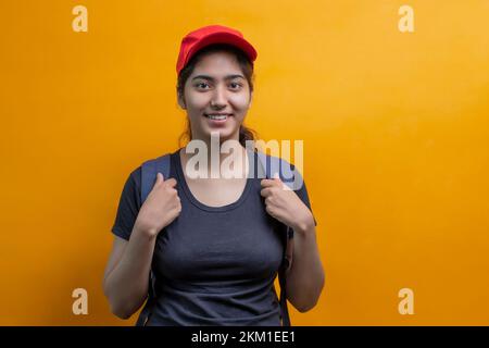 PORTRAIT D'UNE FEMME DE LIVRAISON DEBOUT AVEC UN SAC REGARDANT HEUREUSEMENT L'APPAREIL PHOTO Banque D'Images
