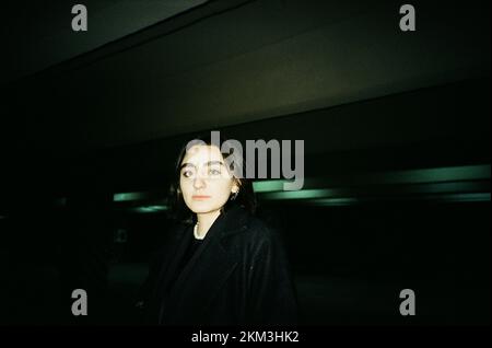 Un portrait d'une belle femme caucasienne aux cheveux courts foncés posé dans un parking souterrain sombre tourné sur film Banque D'Images