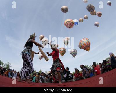 Les danseurs Lengger de Wonosobo Regency, Central Java, Indonésie dansent sur fond de ballons à air chaud Banque D'Images