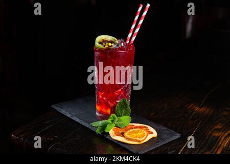 Gros plan sur un cocktail artisanal de rhum et de soda gastronomique de mode ancienne, garni de chaux, d'orange et de menthe séchées sur le bar tendre au backgro foncé Banque D'Images