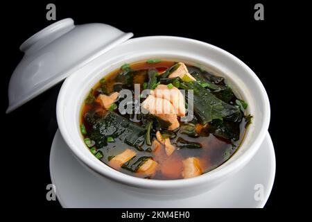 Soupe miso avec saumon, algues et oignons, sur fond noir Banque D'Images