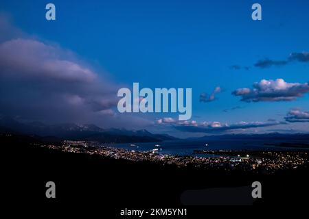 La ville d'Ushuaia, en Argentine, la nuit, où le port rencontre la ville et les montagnes en arrière-plan. Banque D'Images