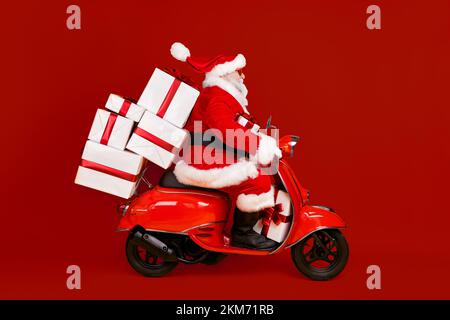 Profil vue de côté de son il Nice drôle FAT St Nicholas Driving Motor bike hâte de livrer pile de cadeaux Eve Noel tradition d'hiver isolée Banque D'Images