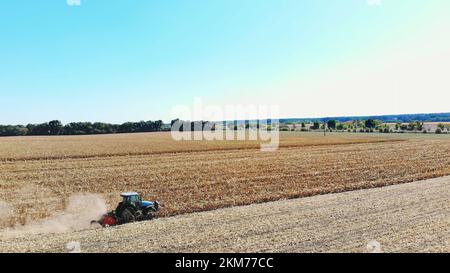 Vue de dessus de l'antenne. le tracteur coupe les tiges et les feuilles de maïs sèches après la récolte du maïs. Agriculture aérienne. début de l'automne. Photo de haute qualité Banque D'Images