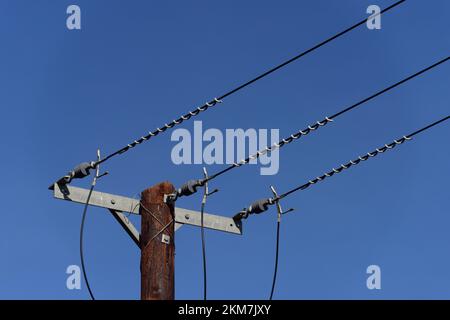 Câbles d'alimentation aériens sur un poteau contre un ciel bleu. Banque D'Images