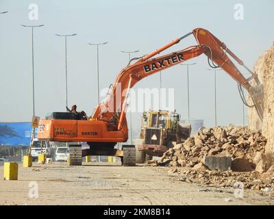 Le Caire, l'Egypte, 26 novembre 2022: Excavatrice hydraulique de démolition sur chenilles enlever les prats d'une colline ou d'une montagne sur le bord de la route pour développer et élargir t Banque D'Images