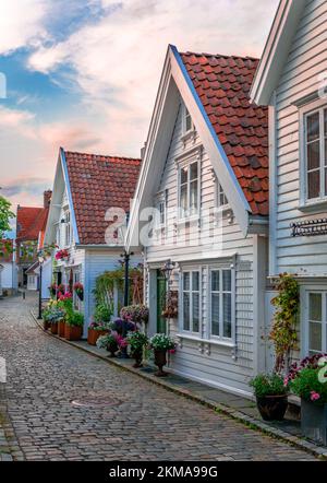 Vue sur Øvre Strandgate, dans la vieille ville de Stavanger, Norvège. Maisons en bois blanc décorées de belles fleurs dans des rues pavées rustiques. Banque D'Images