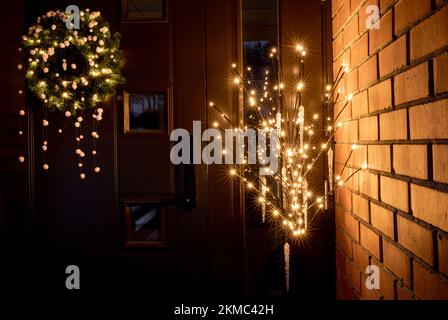 Maison porte entrée à l'extérieur avec différentes décorations de Noël couronne de Noël avec pompons et pot de fleur avec arbre artificiel avec lumières. Banque D'Images