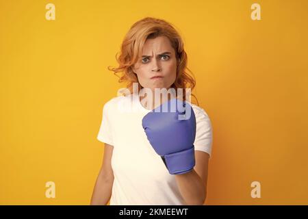 Femme en colère dans des gants de boxe isolés sur fond jaune. Banque D'Images