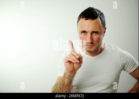 Homme beau adulte avec barbe portant un t-shirt blanc sur fond bleu visage heureux souriant avec bras croisés regardant l'appareil photo. Une personne positive se place strictement dans le cadre Banque D'Images