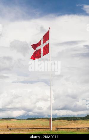 Drapeau danois sur un mât contre un beau ciel nuageux Banque D'Images