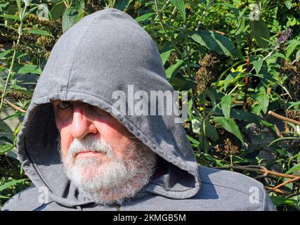 un vieil homme en colère se cachant sous le capot et regardant se mettre en danger vers la caméra. Banque D'Images