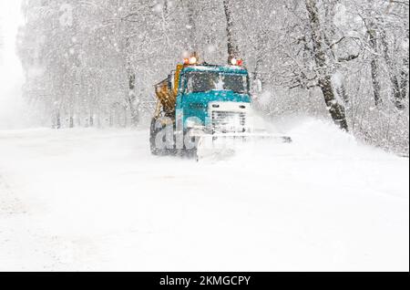 Chasse-neige camion nettoyant la route enneigée en tempête de neige. Chute de neige sur l'allée. Banque D'Images