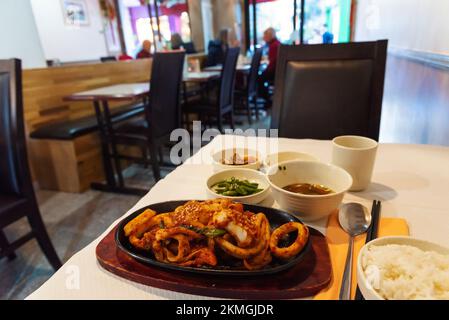 Calmars et soupe frits, riz, kimchi et légumes en accompagnement dans un restaurant coréen authentique servant des plats frais traditionnels simples. Paris, France. Banque D'Images