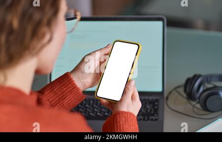 Vue sur l'épaule d'une femme tenant un téléphone portable avec un écran maquette. Banque D'Images