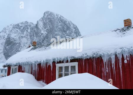 Montagne en pierre en forme de coeur derrière la célèbre attraction touristique village de pêcheurs de Hamnoy sur les îles Lofoten, Norvège avec des maisons de rorbu rouge. Avec chute Banque D'Images