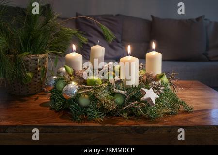 Troisième Avent, couronne avec trois bougies blanches allumées et décoration de Noël sur une table en bois devant le canapé, décoration de fête, espace de copie Banque D'Images