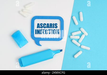 Médecine et concept de santé. Sur une table blanche et bleue se trouvent des pilules, un marqueur et une plaque bleue avec l'inscription - infection d'Ascaris Banque D'Images