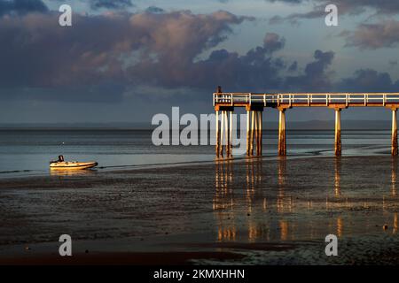 Personnes debout sur Scarness Jetty au coucher du soleil à marée basse, Scarness, Hervey Bay, Queensland Australie Banque D'Images