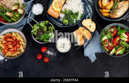 Ensemble de plats principaux variés. Différents plats sains, plats de viande et de poisson, pâtes, salades, sauces, pain et légumes sur fond sombre. À Banque D'Images