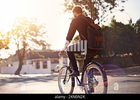 Je préfère être à cheval. Vue arrière d'un jeune homme à vélo en plein air. Banque D'Images