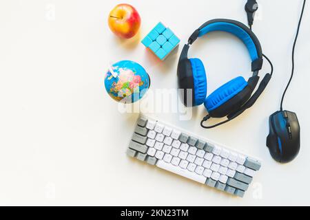 Au-dessus de la vue de dessus, concept d'espace de travail étudiant, souris, clavier, casque sur fond blanc avec espace de copie et développement des enfants. Études élémentaires à distance Banque D'Images