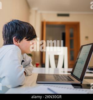 Un garçon d'école sérieux s'est concentré tout en étudiant les mathématiques à la maison. École à domicile et enseignement à distance Banque D'Images