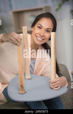 femme fixant des jambes en bois sur un tabouret Banque D'Images