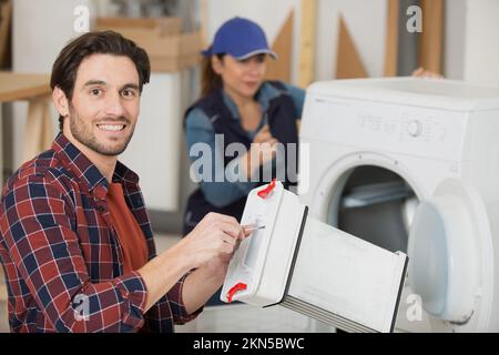 réparateur tenant le condensateur du sèche-linge Banque D'Images