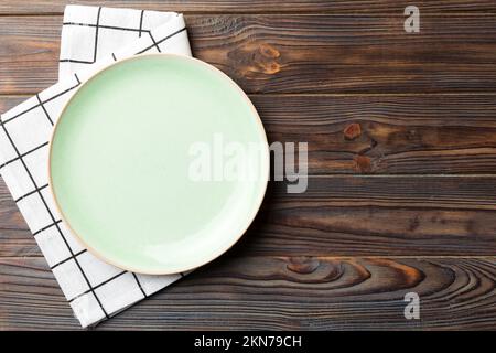 Vue de dessus sur fond coloré vide autour de la plaque verte sur la nappe pour la nourriture. Videz le plat sur la serviette avec de l'espace pour votre dessin. Banque D'Images