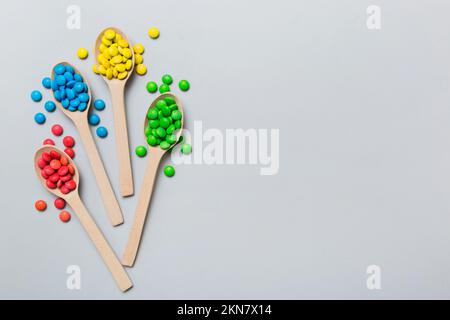 délicieuses sucreries douces colorées sur une cuillère sur fond coloré . Décoration de confiserie, vue de dessus avec espace pour les copies. Banque D'Images