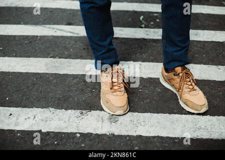 Tenue d'un homme portant des baskets et un Jean bleu marine debout dans une rue de zébré Banque D'Images