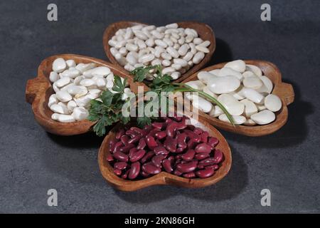 Gros et petit haricots blancs séchés, crus et sains, sur un plat en bois sur une surface en pierre, vue du dessus Banque D'Images