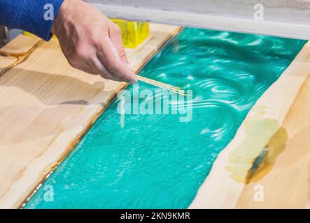 carpenter mélange l'époxy pour créer une trasery sur la table de cuisine Banque D'Images